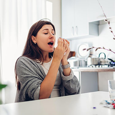 Woman sneezing in home from spring allergies